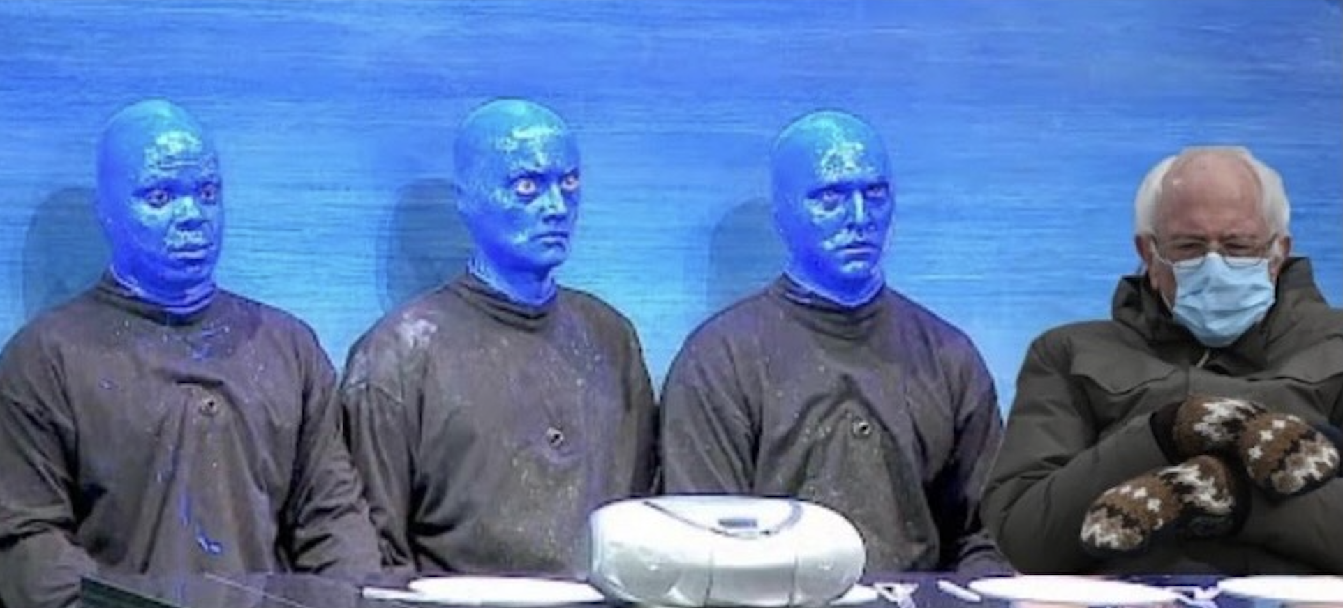 Bernie Sanders seated beside Blue Man Group performers