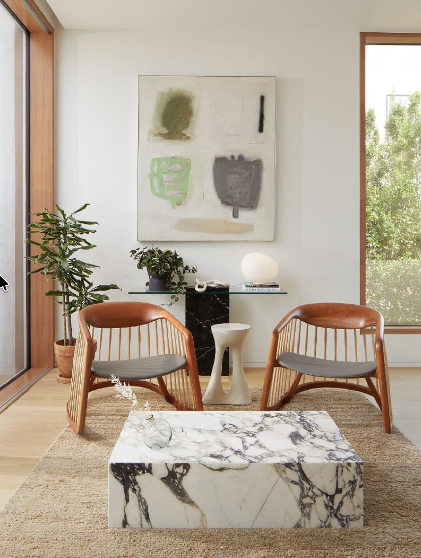 Interior seating area with wooden chairs, marble table, plants, and large artwork